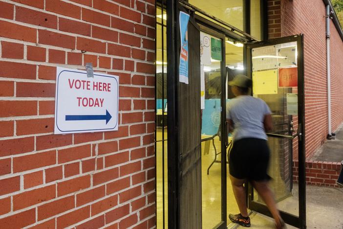 A poll worker heads into the entrance of the Beulah Missionary Baptist Church polling area in Macon Tuesday at the start of voting. 