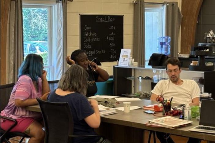 Members of Clubhouse Atlanta sit at a table and look at devices