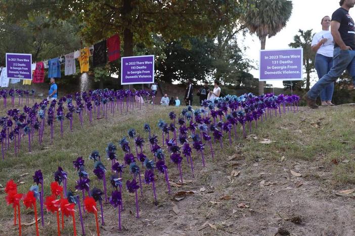 A vigil attendee walks by the pinwheel project as a part of the Domestic Violence Awareness Month candlelight vigil in Washington Square Park on Tuesday, Oct. 29, 2024, in Macon, Georgia. Each pinwheel represents one death from domestic violence in Georgia and the red pinwheels represent deaths in Middle Georgia. Katie Tucker/The Telegraph