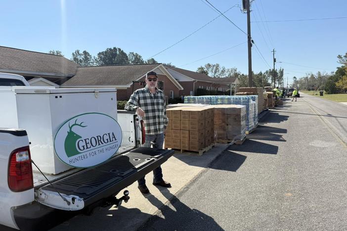 A man stands next to a truck with a Georgia Hunters for the Hungry logo, and eight hundred pounds of venison.