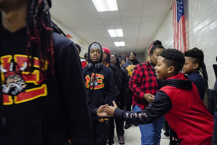 RJ Veal, a right, a fourth grader at Macon's Bernd Elementary School gives five to a member of Macon's Northeast High School Raiders football team at the start of the team's tour of all the schools feeding Northeast High Monday. The team made the trip ahead of their GHSA championship game against Toombs County. 