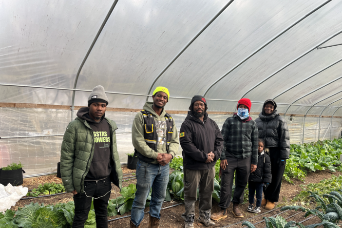 Participants in Gangstas to Growers stand in the greenhouse at Phoenix Garden in Lawrenceville, GA. 