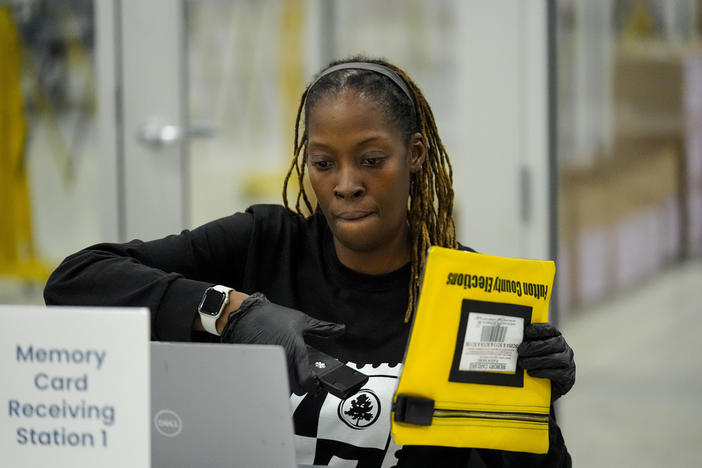 An election worker scans an envelope that holds a voting machine memory card at the Fulton County Election Hub and Operation Center, Tuesday, Nov. 5, 2024, in Atlanta. 