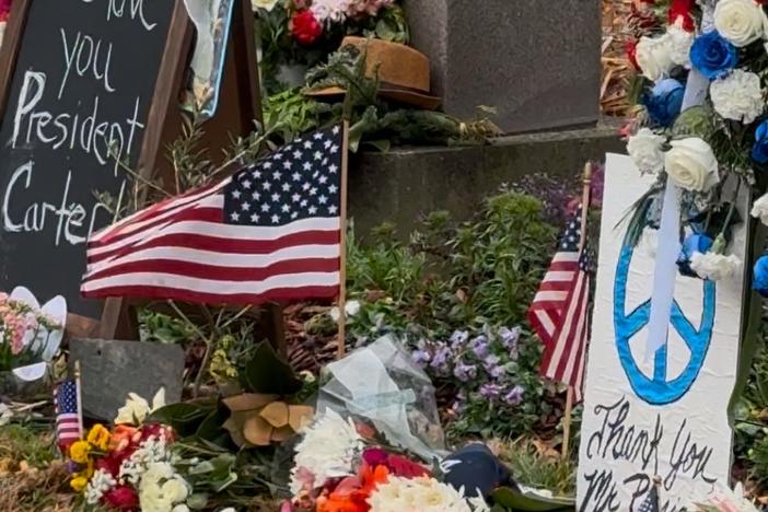 A memorial at the entrance of the Carter Center is covered in flowers, flags and notes from  those who are remembering the life and legacy of former President Jimmy Carter, who died on Dec. 29, 2024.