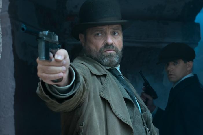 A man standing in a corridor pointing a gun.