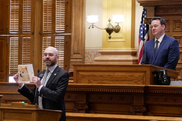  Sen. Josh McLaurin, a Sandy Springs Democrat, holds up a photo of the Doge meme that became popular in 2013 while Lt. Gov. Burt Jones looks on. 