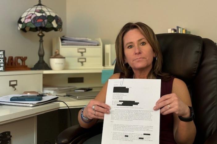 Tracy Hooper holds a redacted letter from her insurance company