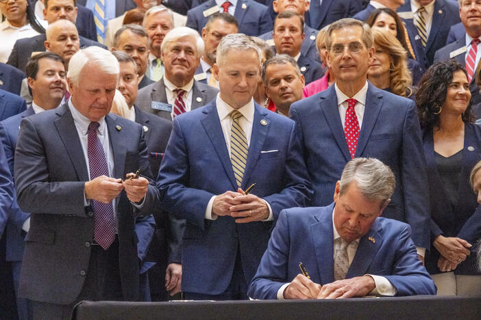 Georgia Governor Brian Kemp, flanked by House Majority Leader Jon Burns and bill sponsor Sen. John F. Kennedy, signs Senate Bill 68 on Monday. The bill, now law, will drastically change the way liability suits play out in state courts and faced some opposition this session, before ultimately passing both chambers.