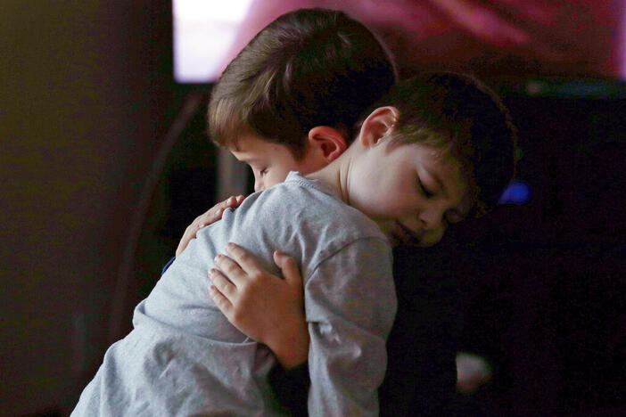 In this Saturday, Dec. 12, 2015 photo, Tyler Volz-Benoit, who is autistic, rests his head on the shoulder of his adoptive brother Ryan, who gives him a hug at their family home in Springfield, Mass. 