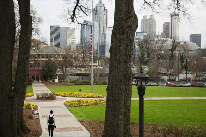 A pedestrian walks through the Georgia Tech campus as the downtown Atlanta skyline looms in the background, March 11, 2016. 