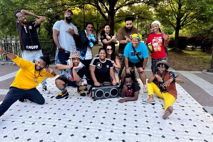 Anthony "Fyrefli" Gasaway Jr (back row, third from left) and Joy "Kuma" Gasaway (seated, holding boombox) gather with FyreNation Crew members and cypher participants at Atlanta's Old Fourth Ward Park on April 27, 2025. 