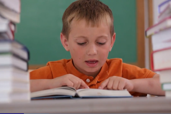young child in orange shirt reading a book