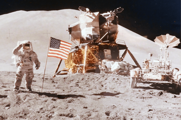 Apollo 15 lunar mission astronaut David R. Scott stands before the lunar lander module and the lunar rover on the surface of the moon in 1971.