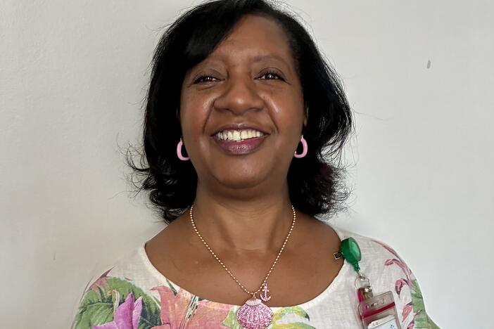 African American woman with chin length hair and a floral shirt smiling at the camera