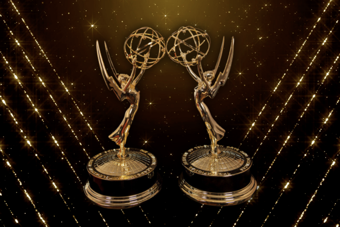 Two Emmy statuettes on top of a glittery background. 
