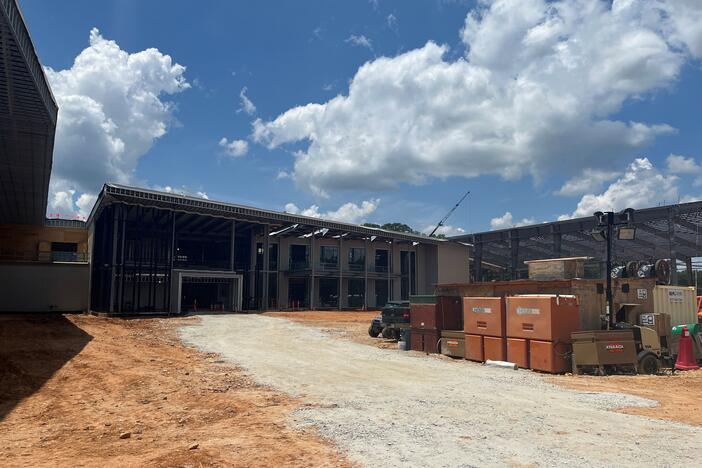 construction materials on a dirt path in front of a large building with no windows or walls yet