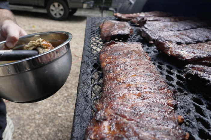 Someone basting a rack of ribs.