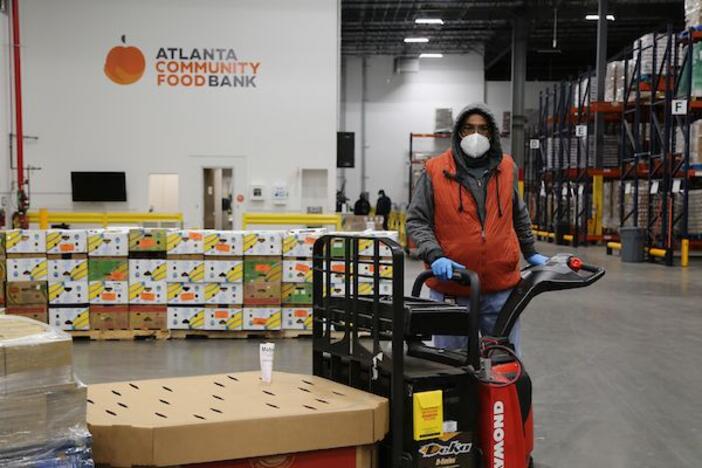 a man with a fork life pallet of food moving through the food bank's warehouse