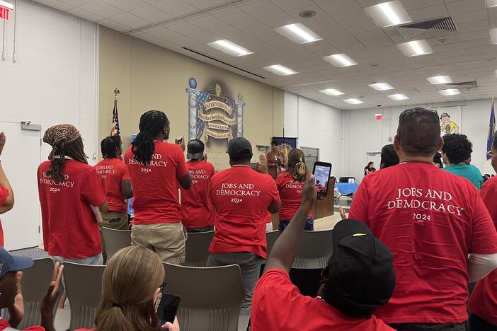 AFL-CIO members standing in red shirts that say "jobs and democracy 2024" on the back.