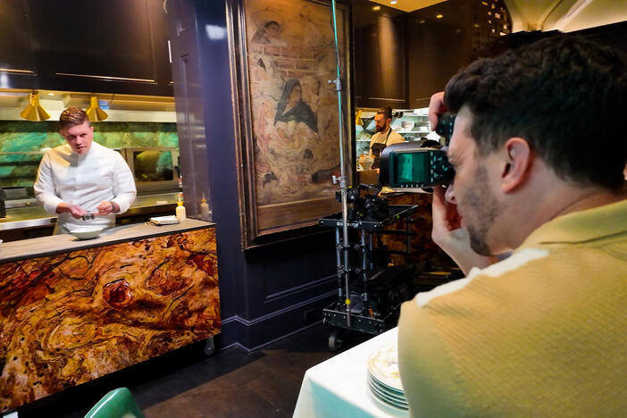 A man photographing someone preparing food.