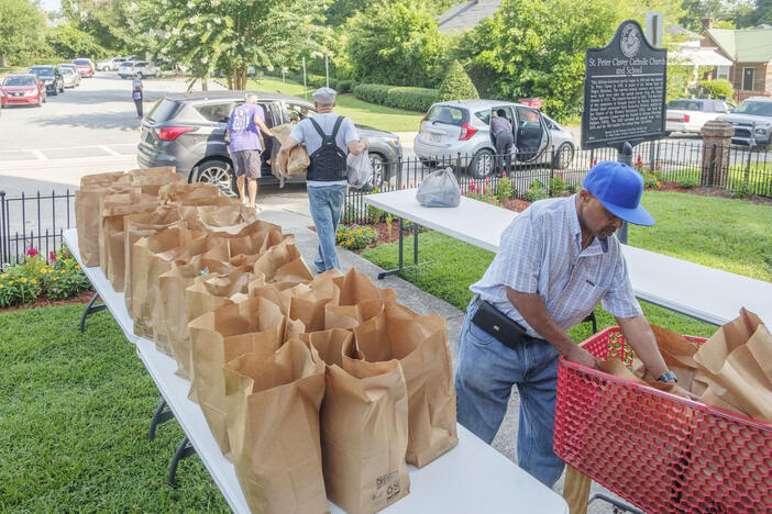 Volunteers share bags of groceries Wednesday with some of the close to 500 families who access food aid at the St. Peter Claver Catholic Church in Macon every week. The St. Peter Claver pantry is just one of over 150 pantries affiliated with the Middle Georgia Community Food Bank. 