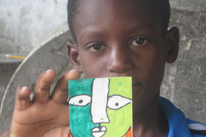 A Haitian student from Project Hope ART holds up his artwork. (Photo courtesy Karen Packer.)