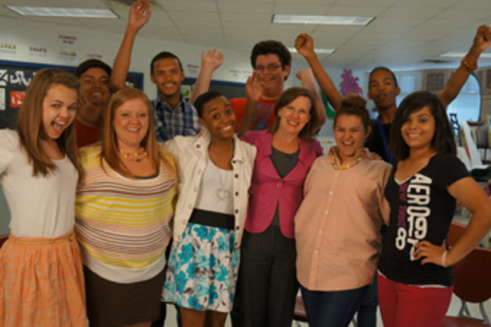 Anne Ostholthoff smiles alongside students from Columbus High School in the premiere episode of The Ignite Show.