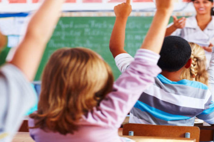 Children raising their hands in a classroom.