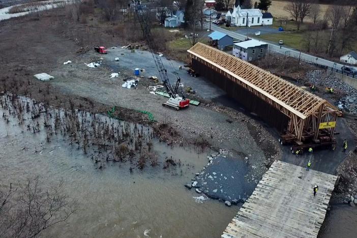 A team scrambles to move a bridge across a rapidly rising creek.