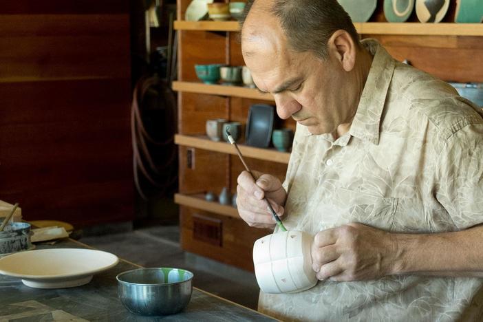 Potter Jeff Oestreich decorates bisque ware.