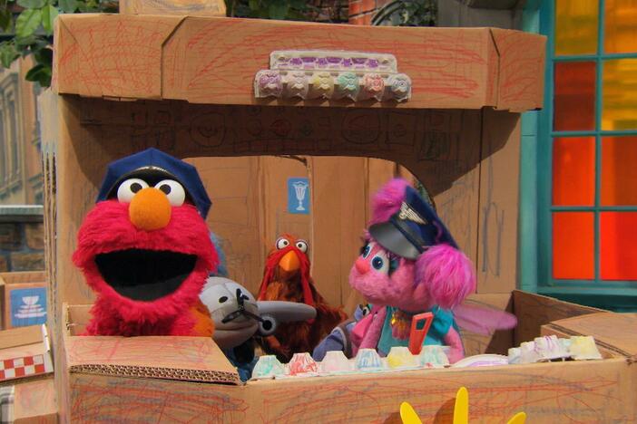 Elmo, Abby, and Rudy sing a song about flying as they play in their cardboard airplane.