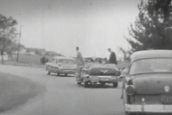 POV shots from inside car, traveling along curvy road w/diplomatic flags flying. 