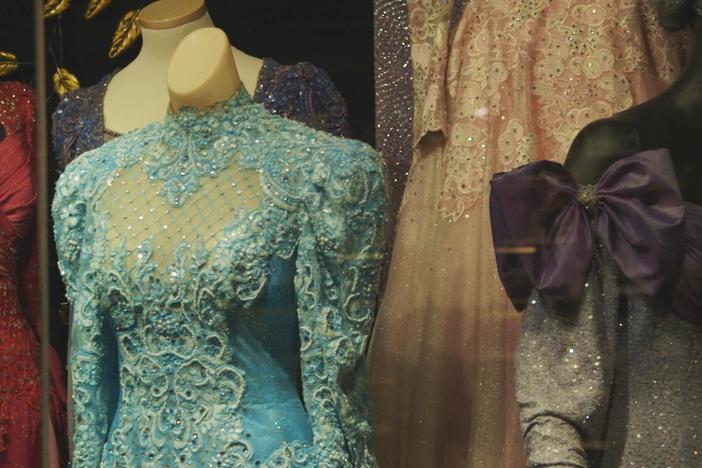 Loretta Lynn's personal designer shows two of her gowns displayed in her museum.