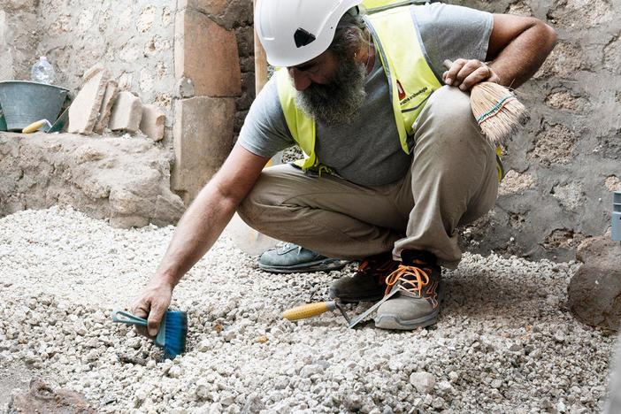 The archaeologists discover expensive marble furniture in the atrium of the wealthy house.