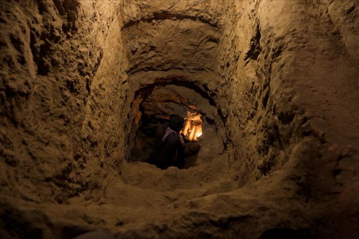 Archaeologists remove the mud brick seal of an unopened Egyptian tomb.