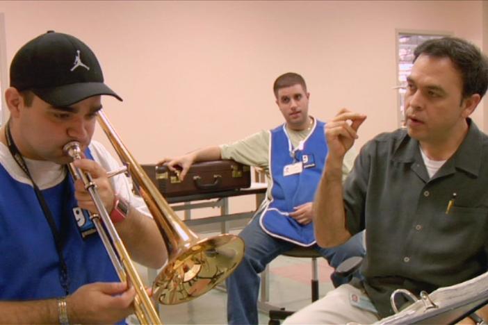 Bandleader Javier Pena coaches trombone player Jary through a rough patch in practice.