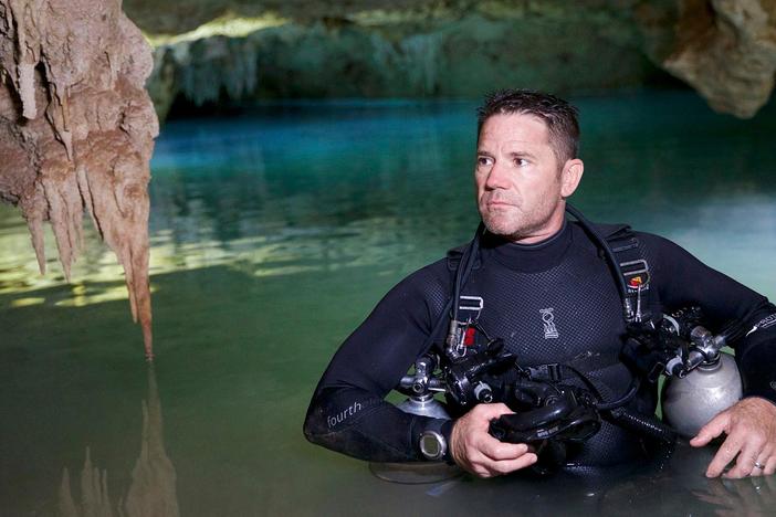Expert diver Robbie Schmittner prepares a guide line for an exploration of a cave.