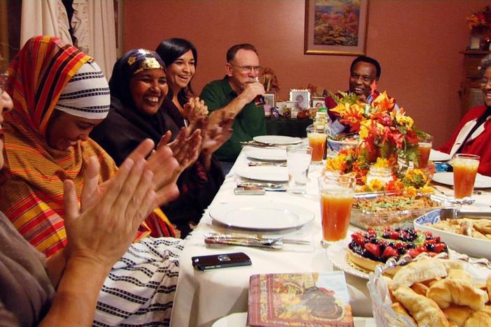 Differences dissolve as bread, company, and customs are shared during a community dinner.
