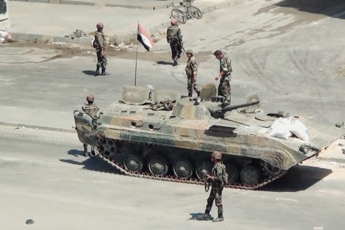 The Syrian military blocks a major thoroughfare and citizens dismantle it.