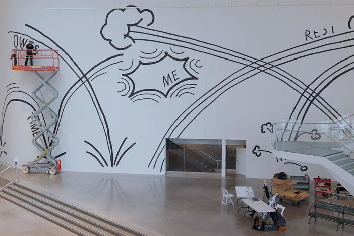 A muralist paints Christine Sun Kim’s work “Time Owes Me Rest Again” at the Queens Museum.