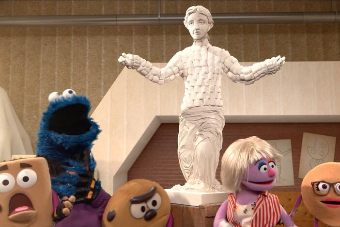 Cookie Monster stops the Crumb's cloud cookie from raining on an artist's sculpture.