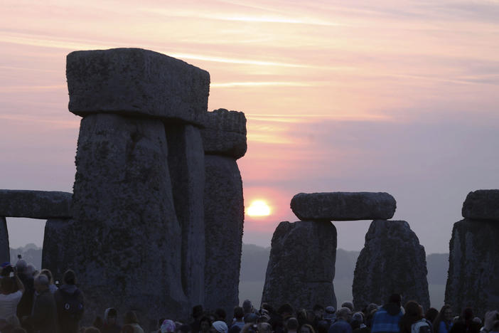 Thousands of people stand among the ancient stones at Stonehenge in Salisbury, England, at sunrise on the summer solstice. Archaeologists on Monday announced the discovery of a ring of shafts about 2 miles away.