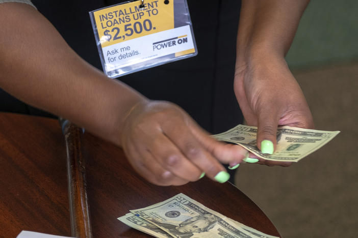 A manager of a financial services store in Ballwin, Mo., counts cash being paid to a client as part of a loan in 2018. Consumer groups blasted a new payday lending rule and its timing during a pandemic that has put tens of millions of people out of work.