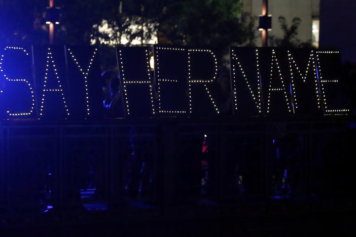 Protesters hold up a lighted sign reading "#sayhername" during a July 2015 vigil for Sandra Bland in Chicago. Bland died in a Texas jail after a traffic stop escalated into a physical confrontation. Authorities said Bland hanged herself, a finding her family disputed.