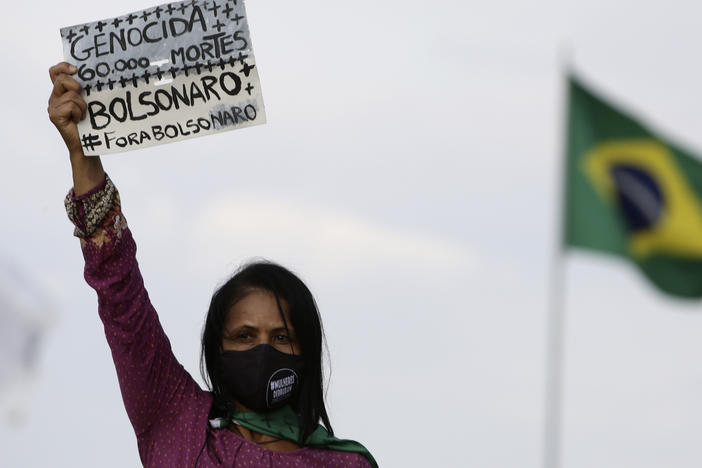 A women's movement activist holds a sign that reads in Portuguese "Genocide 60 thousand deaths, Bolsonaro out" during a protest against the government's handling of the pandemic earlier this month.