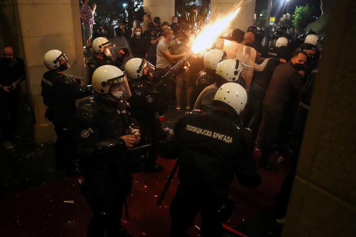 Protesters clash with police Tuesday night in front of the National Assembly building in Belgrade, Serbia.