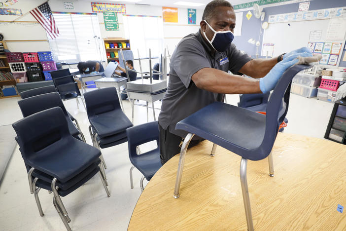 Tracy Harris, a Des Moines Public Schools custodian, cleans chairs at a local elementary school in early July.