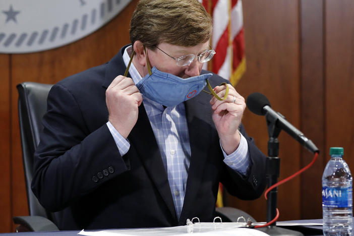 Mississippi Gov. Tate Reeves removes his face mask during a COVID-19 news briefing Wednesday in Jackson.