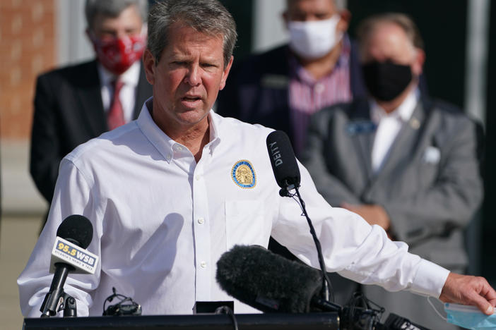 Georgia Gov. Brian Kemp holds a protective mask while speaking during a 'Wear A Mask' tour stop in Dalton, Georgia, earlier this month.