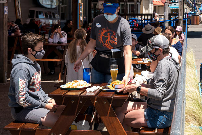 Patrons wear masks as they sit on the outdoor patio of a restaurant on Pier 39 at Fisherman's Wharf in San Francisco. California is among more than 20 states that require face masks to help combat the spread of the coronavirus.